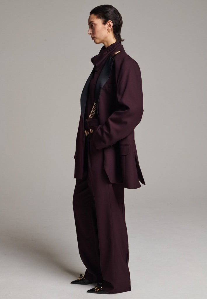 A classic yet oversized blazer, designed to make a bold statement while maintaining timeless appeal. The lower portion of the lapels is crafted from a contrasting shiny fabric, adding an unexpected touch of texture and luxury. The upper part of the collar area is beautifully embellished with gold and silver rings at the tips, offering a refined, modern twist. This piece combines traditional tailoring with avant-garde details, perfect for elevating any outfit with sophistication and edge.