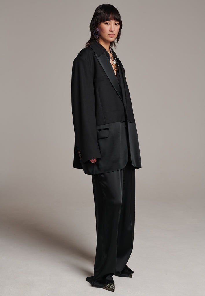 Creative Director Erik Frenken is a master of designing cool, oversized silhouettes, and this blazer is no exception. Precisely tailored with tuxedo-influenced satin lapels and needle point stitching. Full viscose satin lining, handy flap pockets. Horn square button fastenings. This piece will elevate every outfit to the next level, from jeans to dresses, and could easily become your everyday treasure.