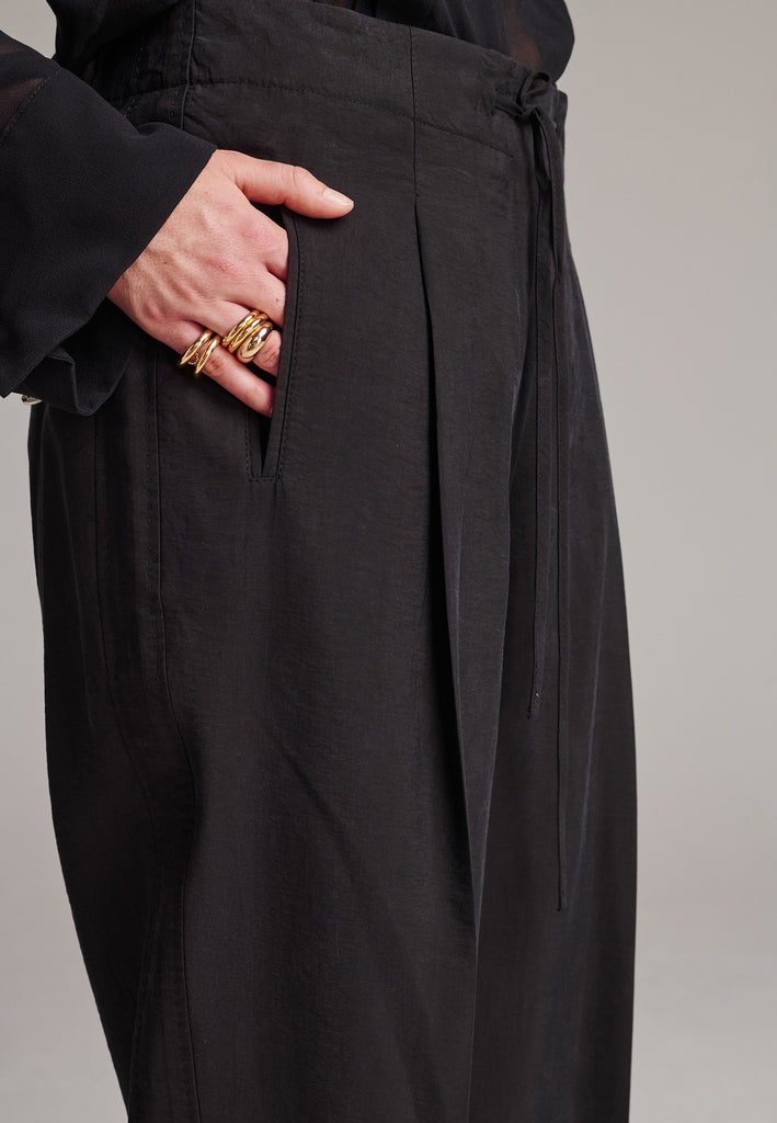 Easy-wear trousers featuring regular cut and drawstring fastening. Detailed with side slit and rear welt pockets. Cut from a light wrinkled viscose with washed look that emphasizes the relaxed attitude. As a nod to the tuxedo pants, it has a self-fabric side seam stripe.