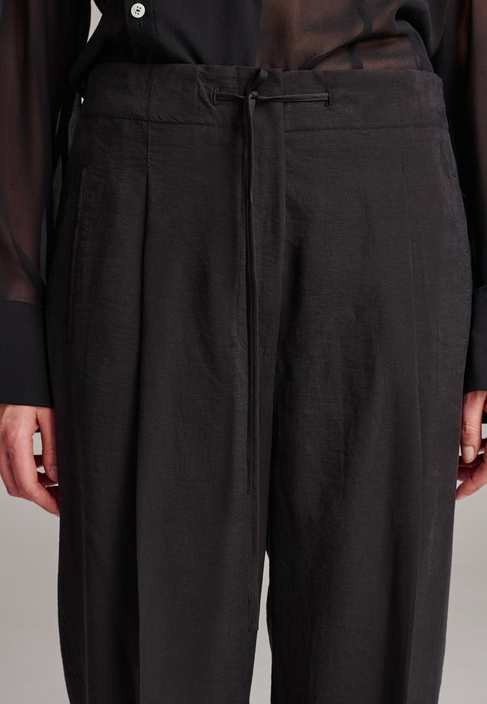 Easy-wear trousers featuring regular cut and drawstring fastening. Detailed with side slit and rear welt pockets. Cut from a light wrinkled viscose with washed look that emphasizes the relaxed attitude. As a nod to the tuxedo pants, it has a self-fabric side seam stripe.
