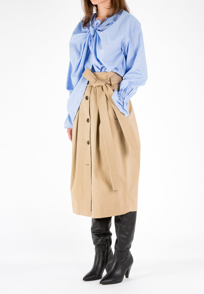 Check light blue shirt. Designed by Eric Frenken. Oversized poplin shirt. Make a knot with two enlarged front panels. Detailed with puffed cuffs. Model wears a size 36.