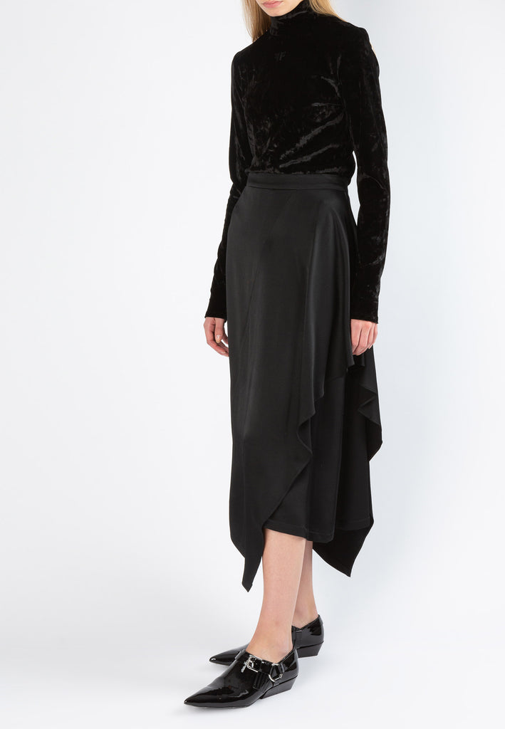 Flapped | Skirt | Black. Asymmetric ruffle midi skirt cut from fluid textured satin. This skirt sits on your natural waist and falls to an asymmetric hem that beautifully sways with each step. Model wears a size 36.