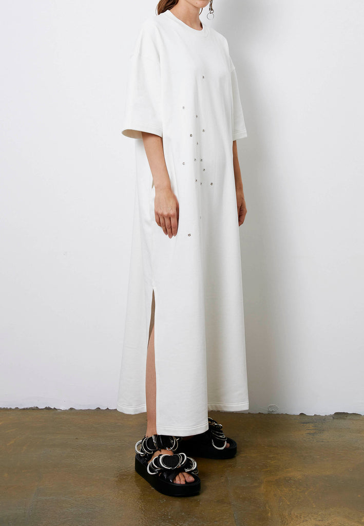 Peak | Dress | Off-white. Maxi dress fabricated in soft off-white interlock. The dropped sleeves emphasize the oversized look, with metallic eyelets and press buttons, inspired by the functionality, for an unexpected leisurewear statement piece. With side slits for extra comfort, to wear inside and out.