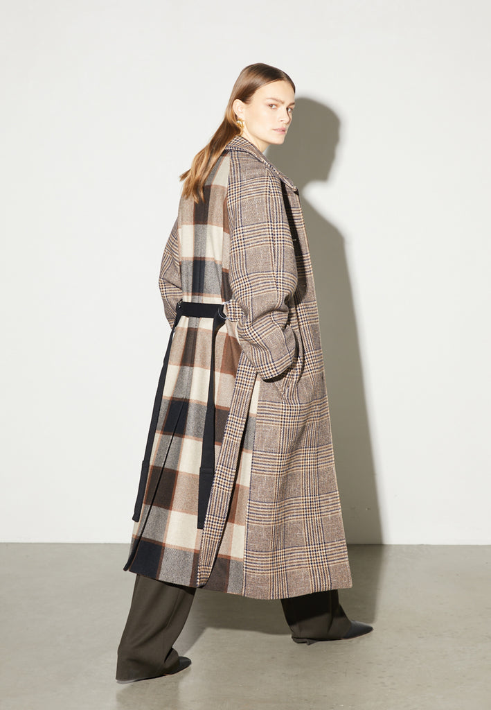 Reaction, an oversized raglan coat that combines two plaid fabrics in shades of brown, with front buttons and a D-ring strap tie that changes from the front to the back. This is the coat of the season, a total game-changer. You can style it with a tracking suit or with a working suit, either way, any look will feel complete with this statement coat.