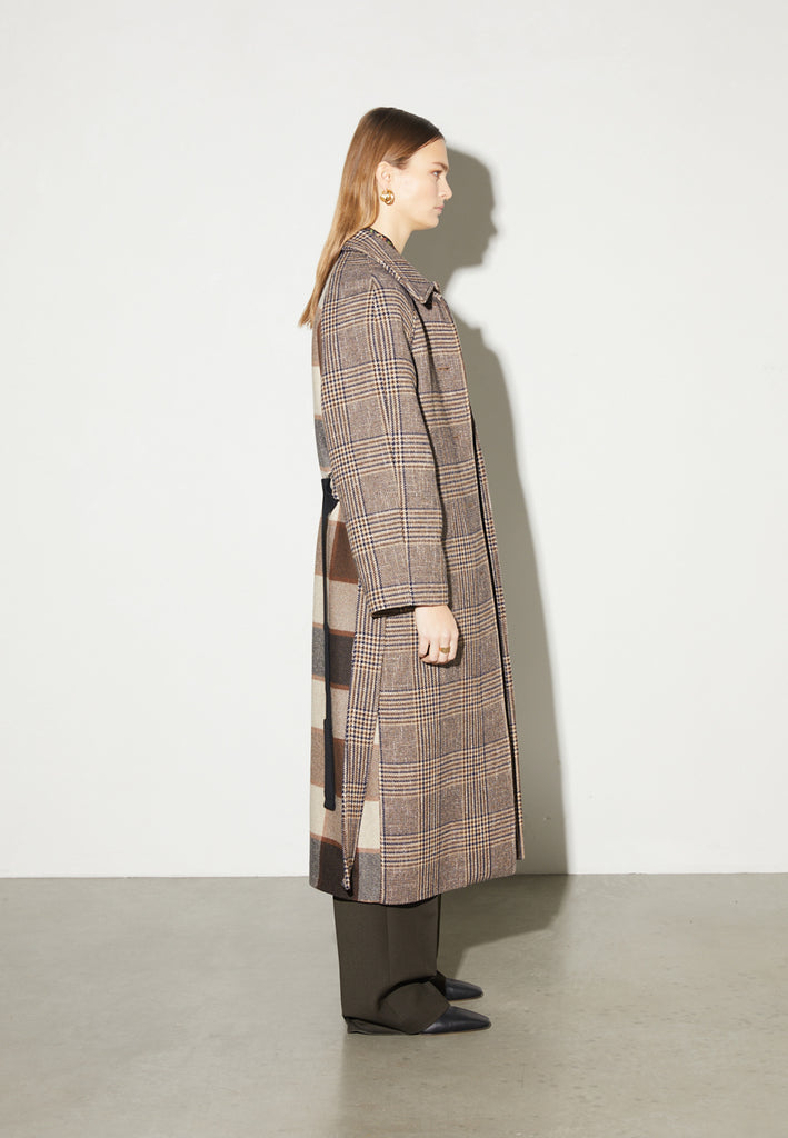Reaction, an oversized raglan coat that combines two plaid fabrics in shades of brown, with front buttons and a D-ring strap tie that changes from the front to the back. This is the coat of the season, a total game-changer. You can style it with a tracking suit or with a working suit, either way, any look will feel complete with this statement coat.