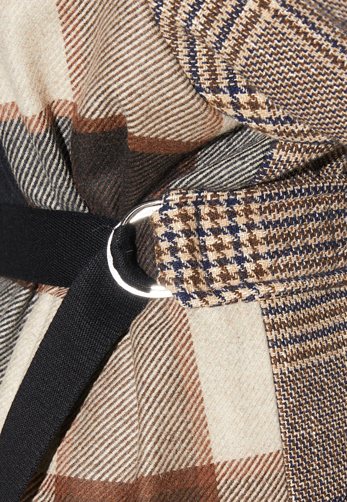 Reaction, an oversized raglan coat that combines two plaid fabrics in shades of brown, with front buttons and a D-ring strap tie that changes from the front to the back. This is the coat of the season, a total game-changer. You can style it with a tracking suit or with a working suit, either way, any look will feel complete with this statement coat.