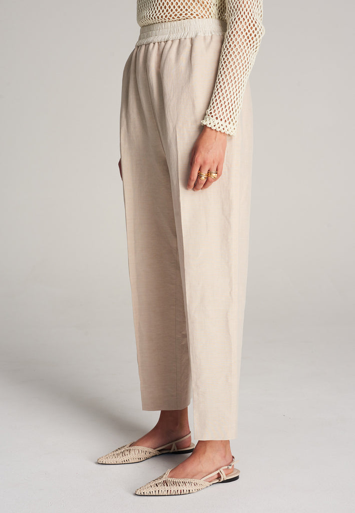FRENKEN Cave beige trouser with a white elastic waistband and side pockets. Accented with softly pressed creases for the perfect fitting. Also available in black.