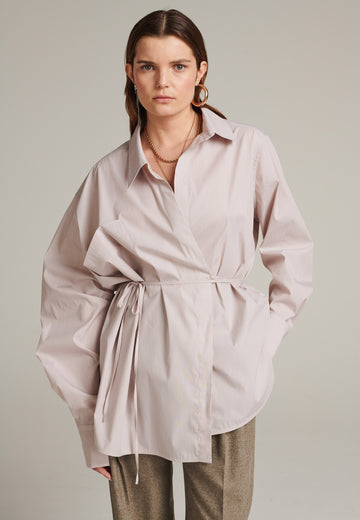 This asymmetric wrapped shirt is made from two different parts sewn together. It's made from 100% cotton poplin in stone, cut for an oversized fit and an unexpected look.