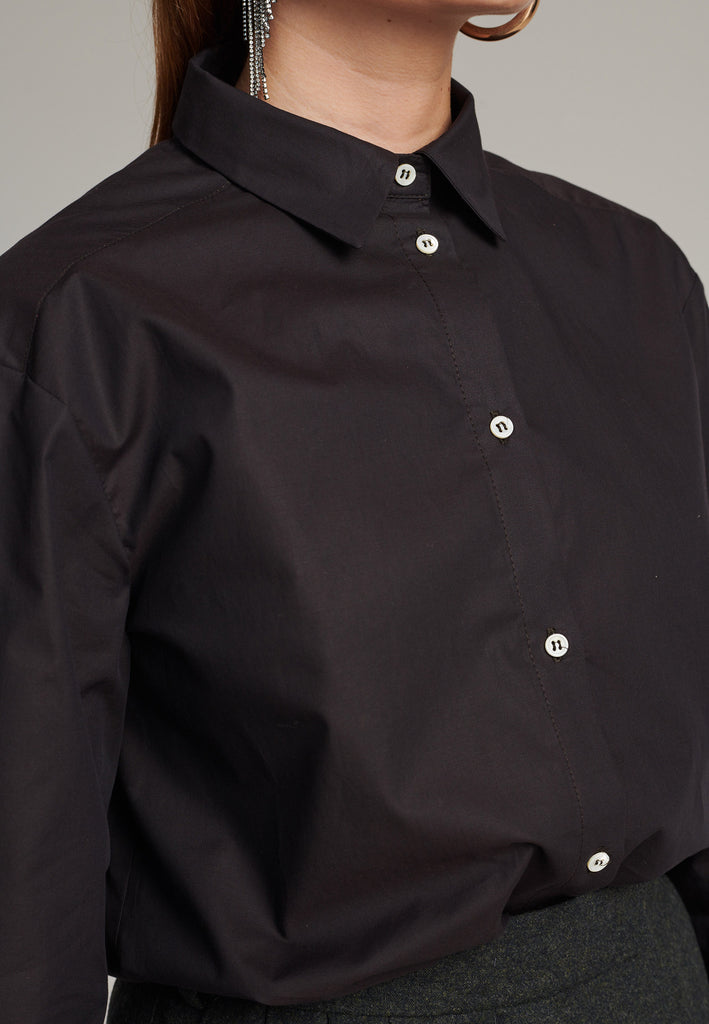 FRENKEN cotton poplin shirt with classic stand collar and button fly-front in choco color. Specially detailed at the back yoke, with the two pannels being joint by a self-fabric string that leaves an elegant cut-out.