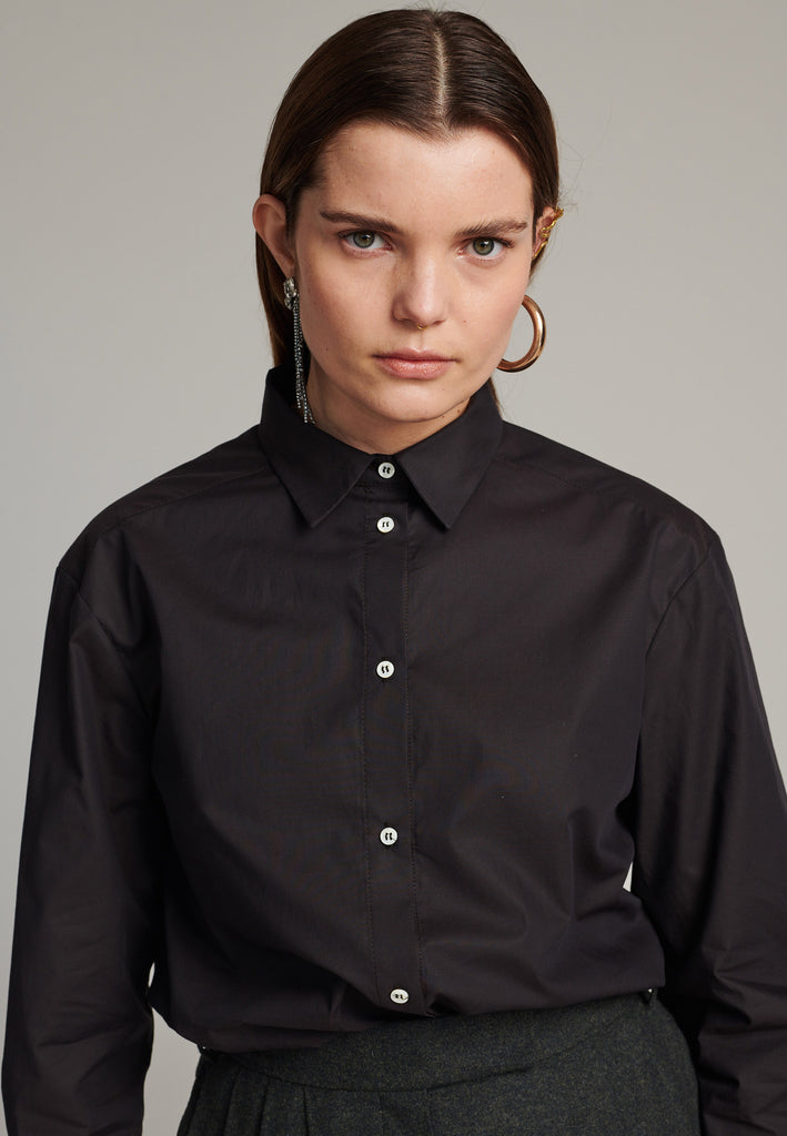 FRENKEN cotton poplin shirt with classic stand collar and button fly-front in choco color. Specially detailed at the back yoke, with the two pannels being joint by a self-fabric string that leaves an elegant cut-out.