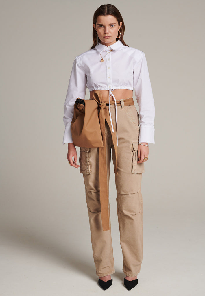 FRENKEN's Best shirt is a directional take on a classic. Cut from white crisp cotton-poplin, it's cropped and gathered at the bust. It has a thin cord closure at the bottom. Sharply padded shoulders detailed with push buttons.