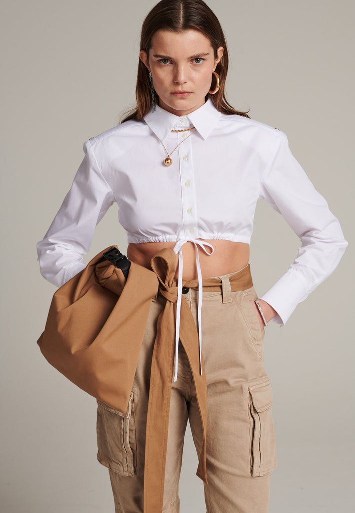 FRENKEN's Best shirt is a directional take on a classic. Cut from white crisp cotton-poplin, it's cropped and gathered at the bust. It has a thin cord closure at the bottom. Sharply padded shoulders detailed with push buttons.