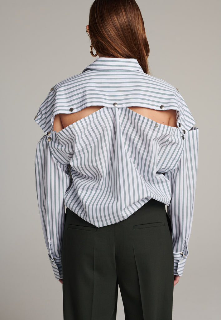 Oversized classic menswear inspred shirt. Cut from 100% crispy poplin cotton in white with dark green thin stripes. Detailed with metal press buttons at the armhole and cuffs to detatch them. The back yoke also features press-buttons! You can play with it by opening or closing the back cut-out.