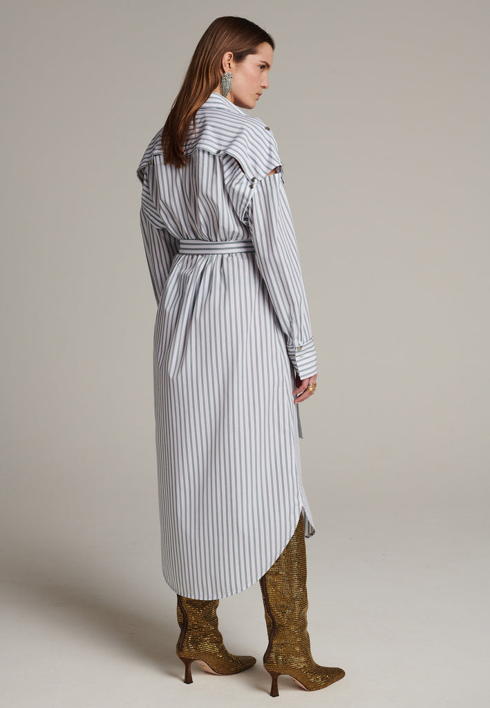 Oversized classic menswear inspred shirt-dress. Cut from 100% crispy poplin cotton in white with dark green thin stripes. Detailed with metal press buttons at the armhole and cuffs to detach the sleeves and cuffs. The back yoke also features press-buttons and you can play with it by opening or closing the cut-out. Designed for a very relaxed fit, use the self-fabric belt to temper the waist.