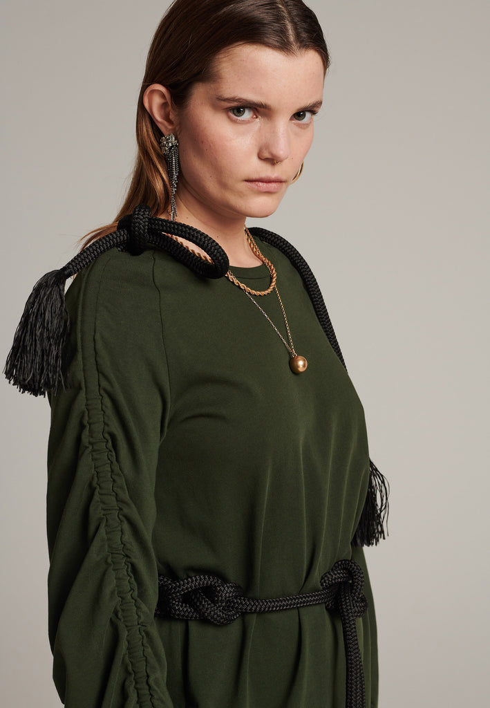 FRENKEN oversized jersey dress with long wide sleeves crafted in soft light dark green cotton, detailed with this season's cord theme. The chunky cords are displayed along the sleeves and can be pulled out to create shape and to shorten the sleeves, making the most of this statement style. The cord ends are hand frayed, a refined couture detail.