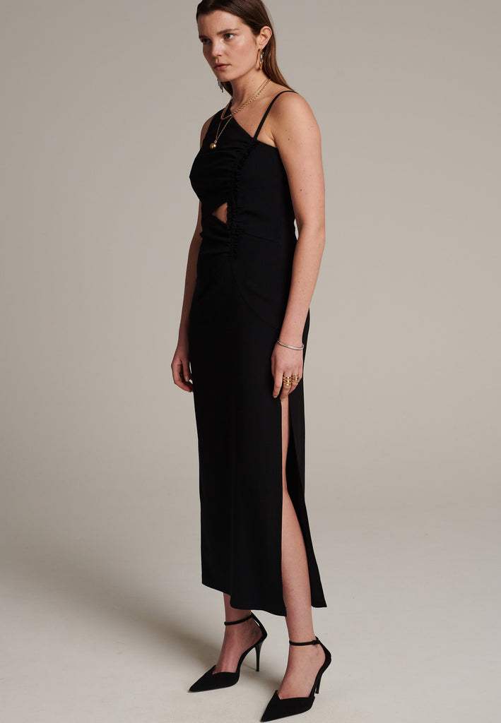 Long evening dress with an asymmetric design made of stretch black wool blend with a subtle gathering at the front to emphasize the silhouette. It has a unique upper part, one delicate shoulder strap and another wider shoulder strap. It has a leg-lengthening side slit for easy movement.