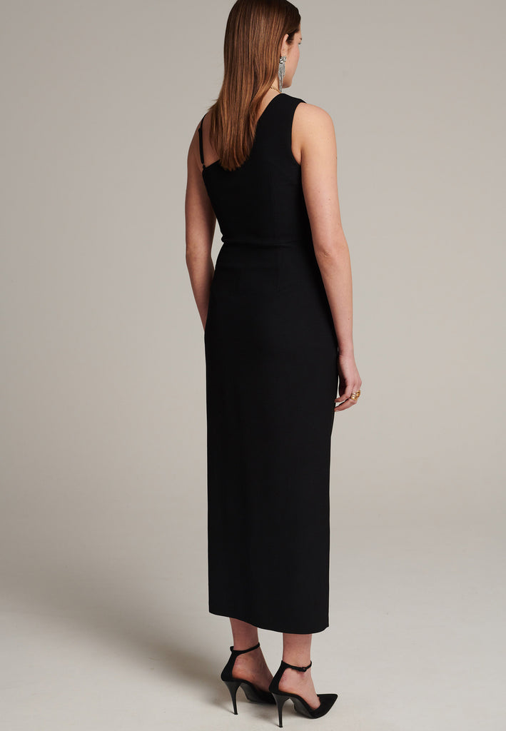 Long evening dress with an asymmetric design made of stretch black wool blend with a subtle gathering at the front to emphasize the silhouette. It has a unique upper part, one delicate shoulder strap and another wider shoulder strap. It has a leg-lengthening side slit for easy movement.