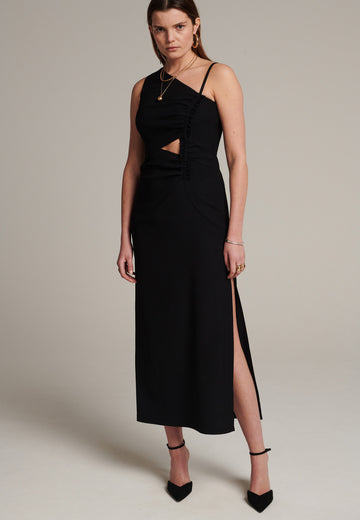 Long evening dress with an asymmetric design made of stretch black wool blend with a subtle gathering at the front to emphasize the silhouette. It has a unique upper part, one delicate shoulder strap and another wider shoulder strap. It has a leg-lengthening side slit for easy movement.