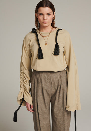 Oversized jersey with long wide sleeves crafted in soft light camel cotton, detailed with this season's cord theme. The chunky cords are displayed along the sleeves and can be pulled out to create shape and shorten the sleeves. The cord ends are hand frayed, a refined couture detail.