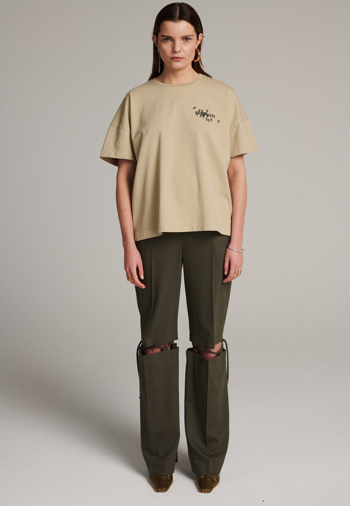 Boyish fitted straight leg trousers cut from fine light wool in dark camel. Detailed with a cut-out section right below the knee, held to the upper panels by a finely laced string. Can be worn elegantly open, loose or tied together.