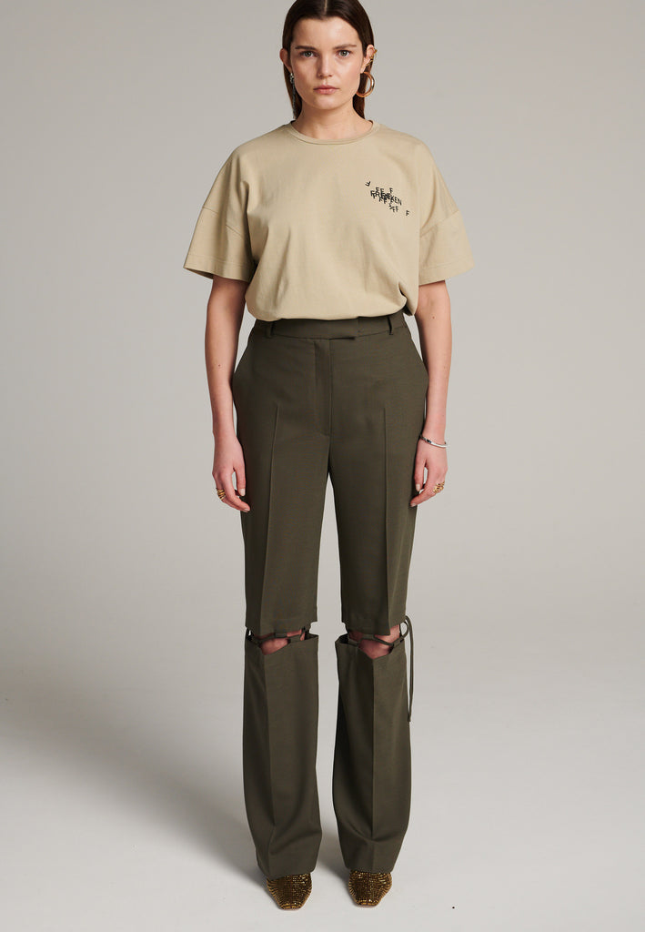 Boyish fitted straight leg trousers cut from fine light wool in dark camel. Detailed with a cut-out section right below the knee, held to the upper panels by a finely laced string. Can be worn elegantly open, loose or tied together.