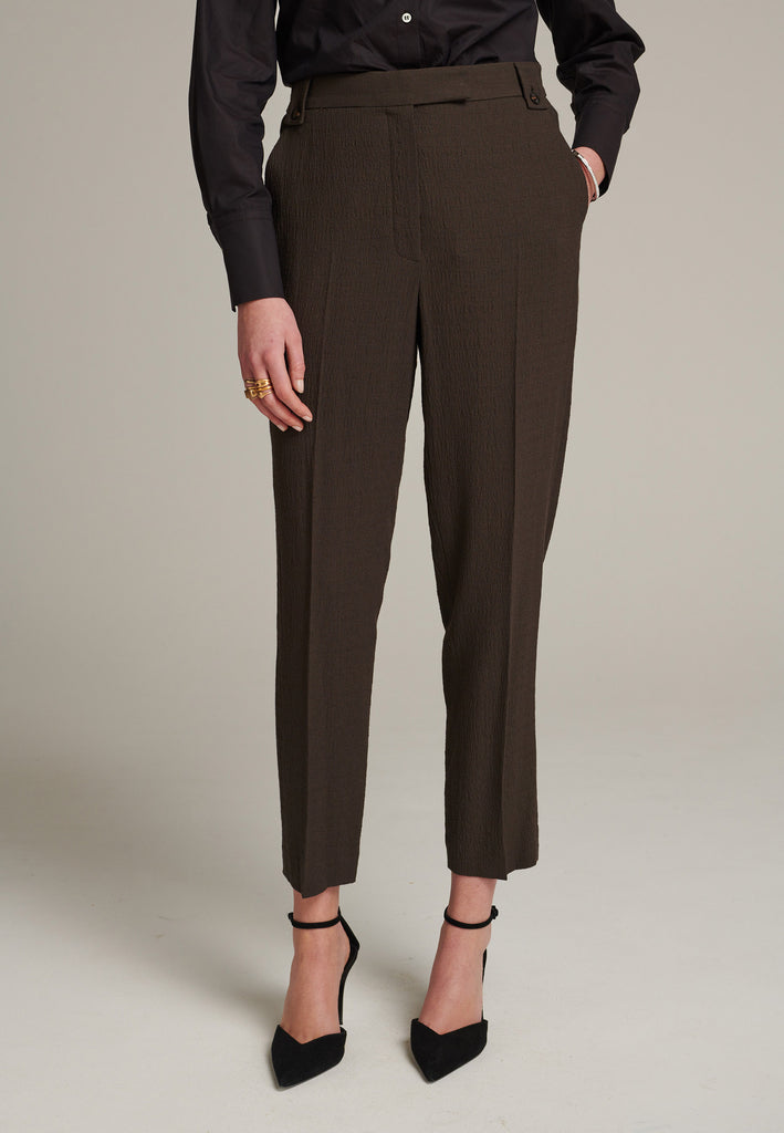 Cropped tailored choco pants cut in a wrinkled light suiting wool blend. Pressed front pleat to emphasize the sophisticated look. Refined with belt loops and horn buttons, welt pocket at the back.