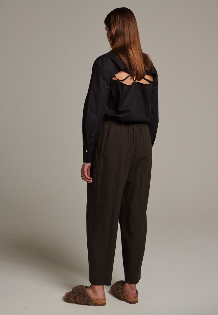 Cropped flowy pants in choco with a high rise. Designed with a loose relaxed fit and drawstring flexible waistband. Pressed front pleat to create a more sophisticated look. Detailed with a welt pocket at the back.