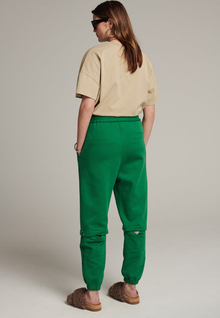 Relaxed fitted sweatpants in green. Cut from soft brushed terry. Detailed with metal press buttons turning the pipes into detachable. Relaxed high-rise silhouette with an elasticated waist and cuffs.