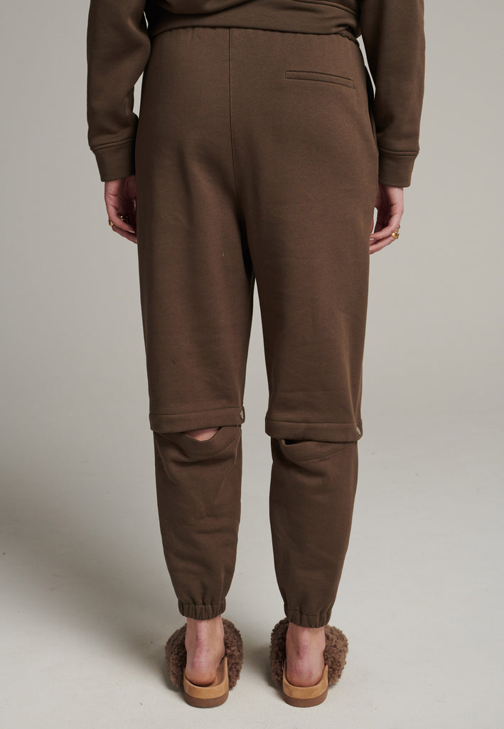 FRENKEN relaxed fitted sweatpants in dark camel. Cut from soft brushed terry. Detailed with metal press buttons turning the pipes into detachable. Relaxed high-rise silhouette with an elasticated waist and cuffs.