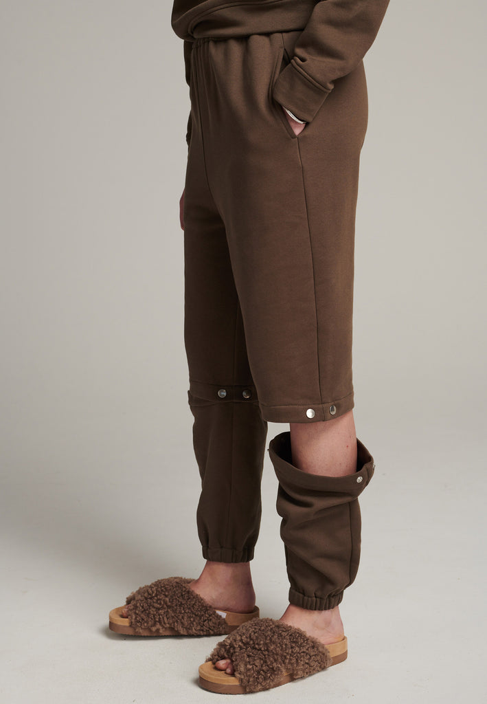FRENKEN relaxed fitted sweatpants in dark camel. Cut from soft brushed terry. Detailed with metal press buttons turning the pipes into detachable. Relaxed high-rise silhouette with an elasticated waist and cuffs.