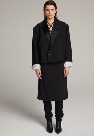 Menswear-inspired smoking blazer with satin lapel, horn buttons, pockets, and shoulder pads for an extreme oversized fitting. The exaggerated long sleeves can be rolled up to reveal a contrasting striped lining. Cut from a fine wool blend, its cropped shape adds a sophisticated touch.
