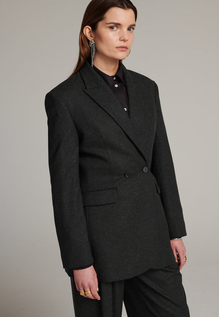 Double-breasted blazer sharply tailored in dark green wool flannel. Wide shoulders are emphasized by the shoulder pads combined with a slim waistline that creates a modern silhouette. Fully lined with satin, horn buttons and flap pockets.