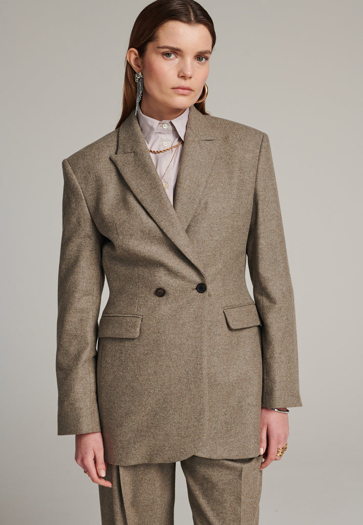 Double-breasted blazer sharply tailored in stone wool flannel. Wide shoulders are emphasized by the shoulder pads combined with a slim waistline that creates a modern silhouette. Fully lined with satin, horn buttons and flap pockets.