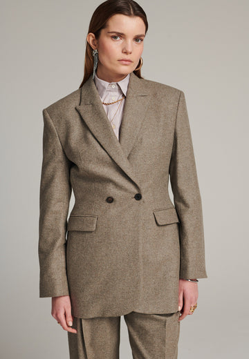 Double-breasted blazer sharply tailored in stone wool flannel. Wide shoulders are emphasized by the shoulder pads combined with a slim waistline that creates a modern silhouette. Fully lined with satin, horn buttons and flap pockets.