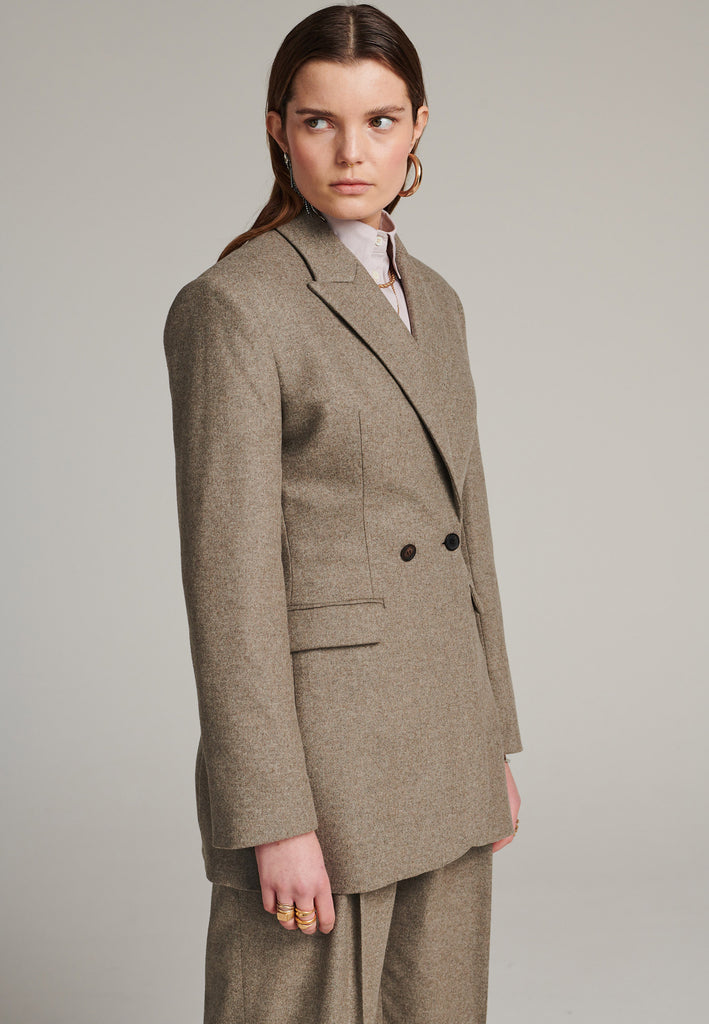 Double-breasted blazer sharply tailored in stone wool flannel. Wide shoulders are emphasized by the shoulder pads combined with a slim waistline that creates a modern silhouette. Fully lined with satin, horn buttons and flap pockets.