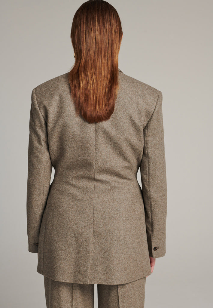 Double-breasted blazer sharply tailored in stone wool flannel. Wide shoulders are emphasized by the shoulder pads combined with a slim waistline that creates a modern silhouette. Fully lined with satin, horn buttons and flap pockets.