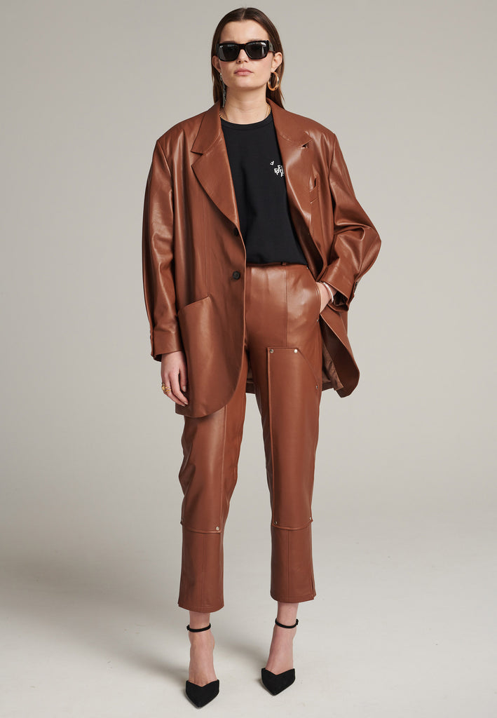 Seasonless oversized leather blazer in cognac with round-shouldered silhouette and coordinating belt that creates some gathering at the back to temper the fitting. Play with it and tie at the smallest part of your waist or tie it at the back for a sense of ease. Pockets, horn buttons and fully lined with. Double fun: wear it as a blazer or as a jacket.