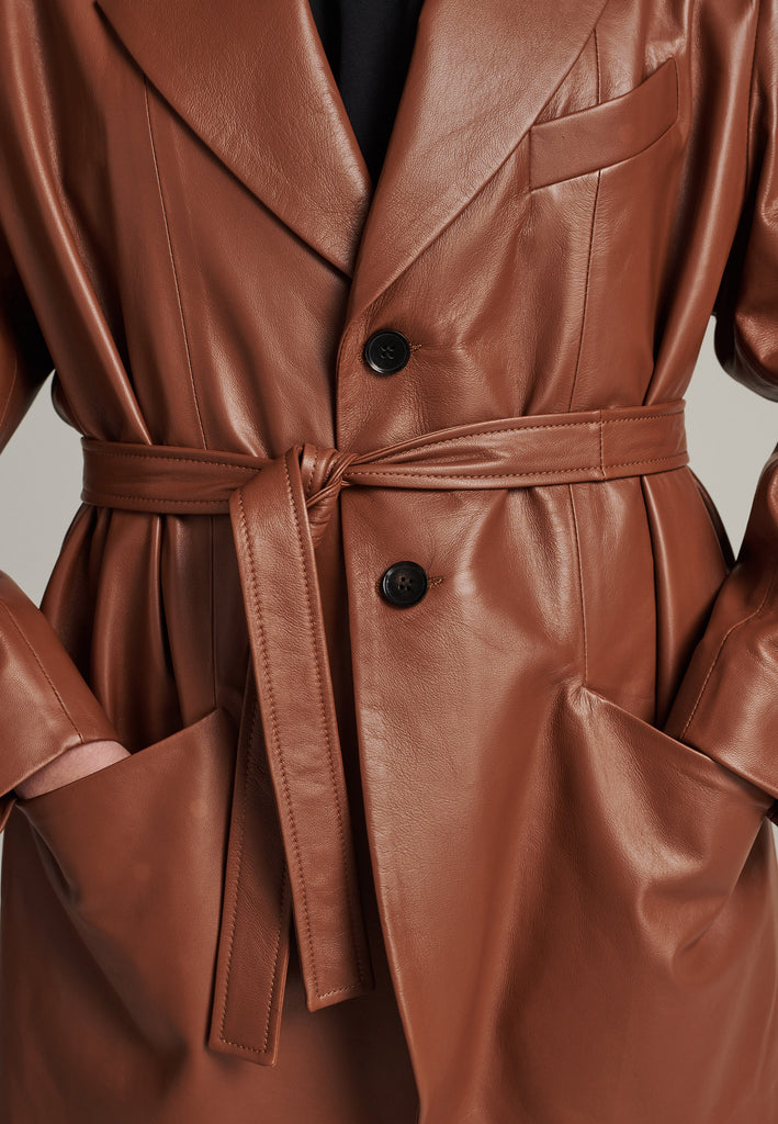 Seasonless oversized leather blazer in cognac with round-shouldered silhouette and coordinating belt that creates some gathering at the back to temper the fitting. Play with it and tie at the smallest part of your waist or tie it at the back for a sense of ease. Pockets, horn buttons and fully lined with. Double fun: wear it as a blazer or as a jacket.