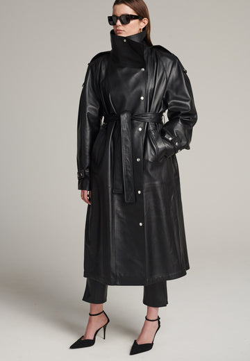 Oversized trench coat crafted in butterly soft lamb leather in black. Detailed with silver metal press buttons at front closure, epaulettes at shoulders and cuffs. Designed with a maxi collar with the snap-fastening buttons and a self-leather belt tp cinch the loose oversized fit.