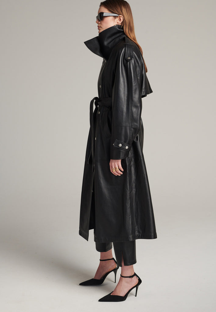 Oversized trench coat crafted in butterly soft lamb leather in black. Detailed with silver metal press buttons at front closure, epaulettes at shoulders and cuffs. Designed with a maxi collar with the snap-fastening buttons and a self-leather belt tp cinch the loose oversized fit.