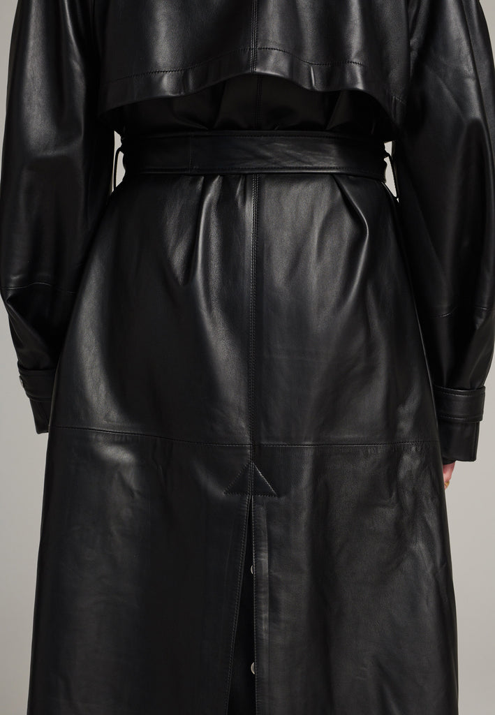 Oversized trench coat crafted in butterly soft lamb leather in black. Detailed with silver metal press buttons at front closure, epaulettes at shoulders and cuffs. Designed with a maxi collar with the snap-fastening buttons and a self-leather belt tp cinch the loose oversized fit.