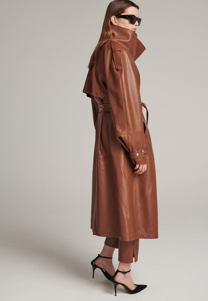 Oversized trench coat crafted in butterly soft lamb leather in cognac. Detailed with silver metal press buttons at front closure, epaulettes at shoulders and cuffs. Designed with a maxi collar with the snap-fastening buttons and a self-leather belt tp cinch the loose oversized fit.