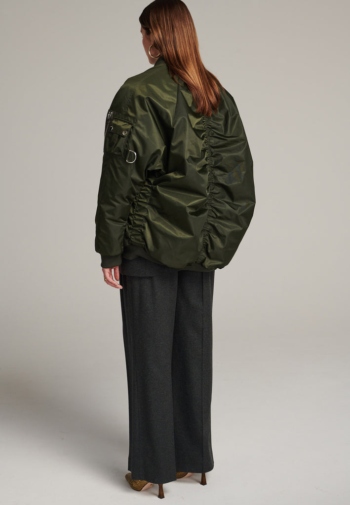 Tramp is already one of FRENKEN classics. This oversized padded bomber jacket in army green is made with heavy water-repellent cloth. Batwing sleeve cut with a wide elastic band under the arm to create a puckering effect at the seams. Detailed with chunky two-way zip. A true creative classic.