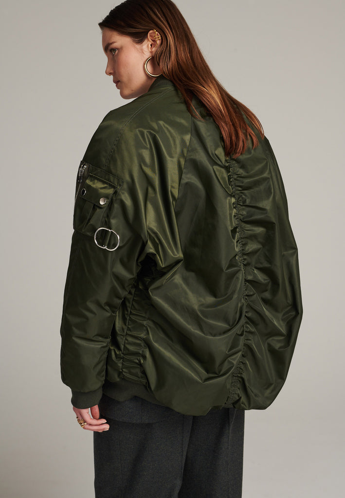 Tramp is already one of FRENKEN classics. This oversized padded bomber jacket in army green is made with heavy water-repellent cloth. Batwing sleeve cut with a wide elastic band under the arm to create a puckering effect at the seams. Detailed with chunky two-way zip. A true creative classic.