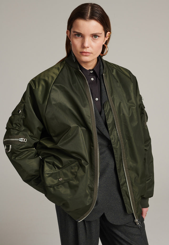 Tramp is already one of FRENKEN classics. This oversized padded bomber jacket in army green is made with heavy water-repellent cloth. Batwing sleeve cut with a wide elastic band under the arm to create a puckering effect at the seams. Detailed with chunky two-way zip. A true creative classic.