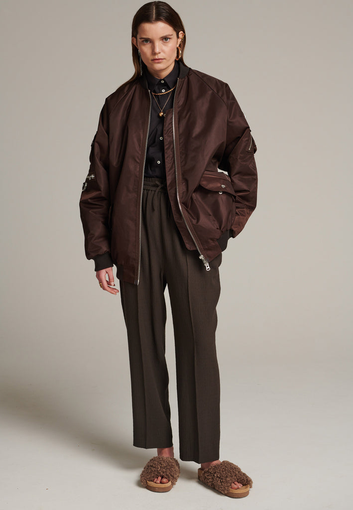 Oversized padded bomber jacket in choco made with heavy water-repellent nylon. Batwing sleeve cut with a wide elastic band under the arm to create a puckering effect at the seams. Detailed with chunky two-way zip. A true Creative classic.