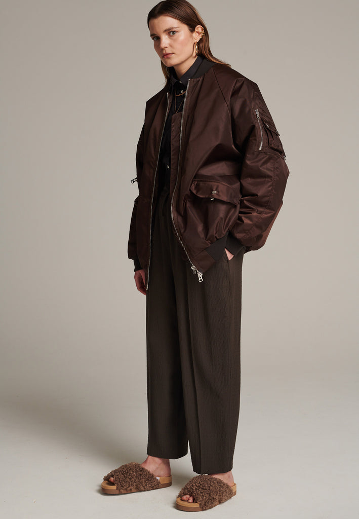 Oversized padded bomber jacket in choco made with heavy water-repellent nylon. Batwing sleeve cut with a wide elastic band under the arm to create a puckering effect at the seams. Detailed with chunky two-way zip. A true Creative classic.