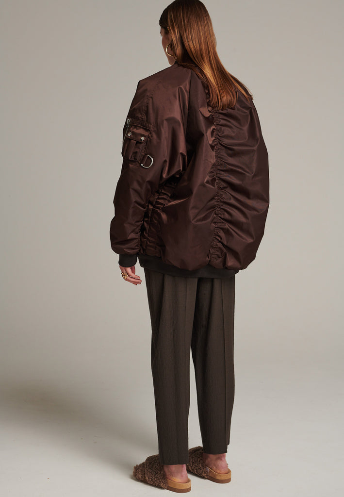 Oversized padded bomber jacket in choco made with heavy water-repellent nylon. Batwing sleeve cut with a wide elastic band under the arm to create a puckering effect at the seams. Detailed with chunky two-way zip. A true Creative classic.