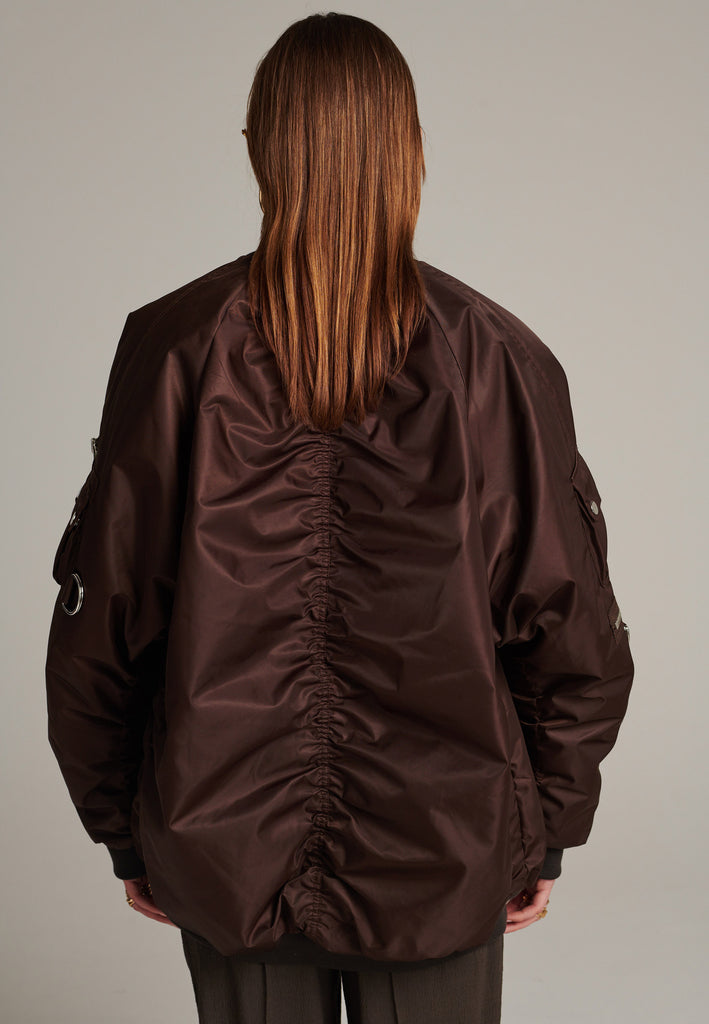 Oversized padded bomber jacket in choco made with heavy water-repellent nylon. Batwing sleeve cut with a wide elastic band under the arm to create a puckering effect at the seams. Detailed with chunky two-way zip. A true Creative classic.