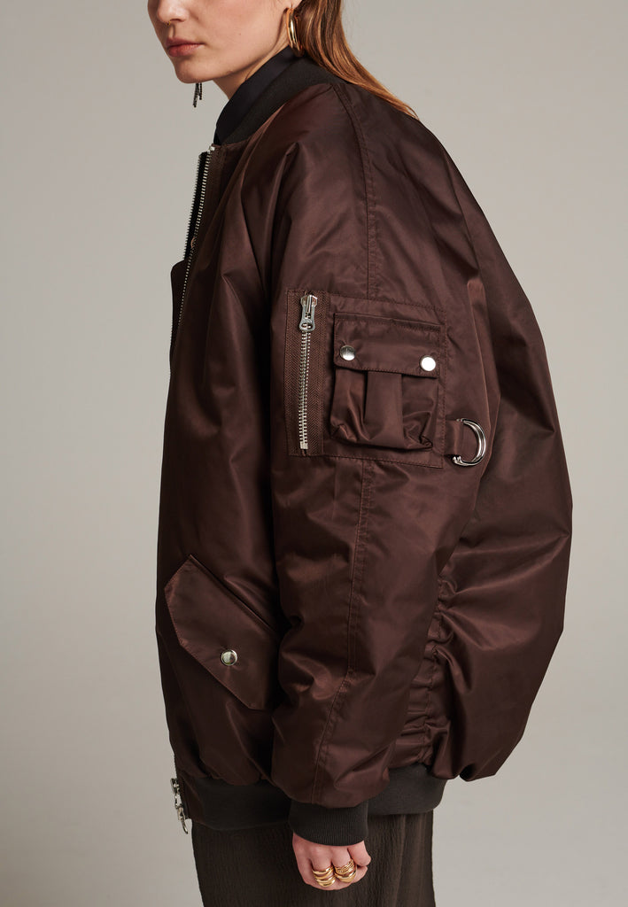 Oversized padded bomber jacket in choco made with heavy water-repellent nylon. Batwing sleeve cut with a wide elastic band under the arm to create a puckering effect at the seams. Detailed with chunky two-way zip. A true Creative classic.